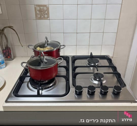 כיריים גז עם סירים אדומים במטבח